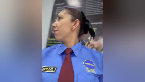 A video of a woman in a blue uniform with a red tie, name tag \"STILLAL,\" and a \"SOS International\" emblem, standing in a blurred indoor setting.