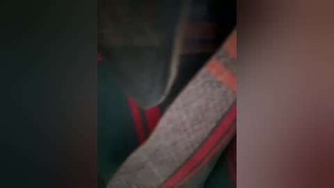 A close-up, slightly blurred video of a person's legs and feet in a red and green striped sock, with a beige sock visible, set against a dark background.