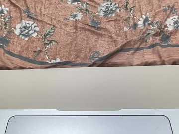 A video of a bedspread with a floral pattern in muted tones of brown, green, and white, and a beige ceiling. The bedspread covers the upper half of the image, with the lower half showing a light-colored ceiling and part of a white wall.