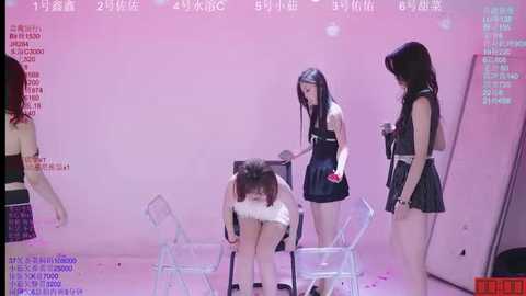 Video of four young Asian women in revealing schoolgirl outfits, holding instruments in a pink-lit, minimalist room. One girl bends over, exposing her buttocks.