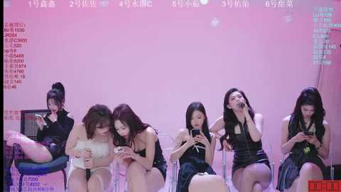 Media: Video of six Asian women in various black dresses, seated on clear chairs, holding smartphones, against a pink background.