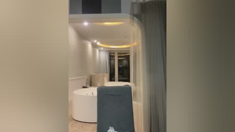 Video of a modern, minimalist bathroom with a white tub, beige tiles, and a gray towel hanging on a door. The room has a warm, inviting ambiance with soft lighting and a sleek, contemporary design.