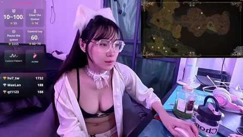 Video of an Asian woman in a revealing maid costume, sitting at a gaming desk, with multiple screens showing game and chat details.