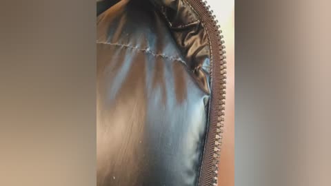 Close-up video of a person's buttocks in tight, shiny black leather pants, showing a zipper and seams. The background is blurred, emphasizing the material texture and fit.