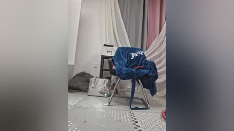 Media: A video shows a messy room with a blue jacket, grey bag, and white sheets. The floor has a grey pattern, and a small table with a printer is visible.