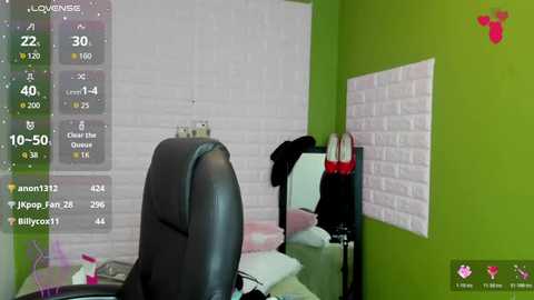 Video of a modern office with a green wall, white brick-patterned wall art, a black leather chair, and a desk with a computer monitor, calendar, and a red purse.