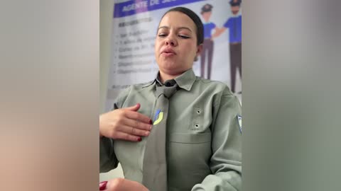 Video of a Latina woman in a uniform, checking her chest with a stern expression. Background includes a blurred sign in Spanish.