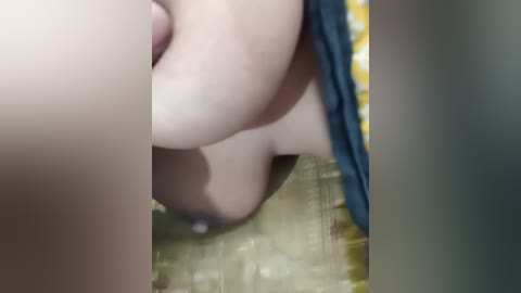 Media: A video showing a close-up of a person's bare buttocks with a yellow and white patterned cloth covering them, partially obscured by another person's hand.