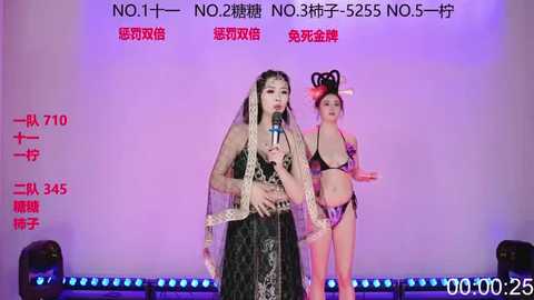 Video of two Asian women in traditional Chinese attire performing on stage. One in a black dress with lace veil, the other in a black bikini. Background includes Chinese text and red numbers.