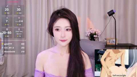 A video of an East Asian woman with long dark hair, light skin, and a slender physique, wearing a lavender off-shoulder top. Background includes a desk with a lamp, a bouquet, and a chair. Overlay shows a video clip of her in a yellow coat.