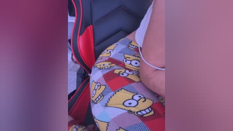 A close-up video shows a person's torso in a white tank top, wearing patterned shorts with the face of a character from \"The Simpsons.\