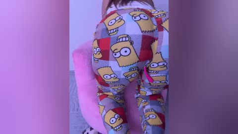 Video of a person's buttocks wearing patterned pajama pants featuring Homer Simpson from \"The Simpsons.\" The pants are white with a red, yellow, and blue design. The background is a light purple wall.