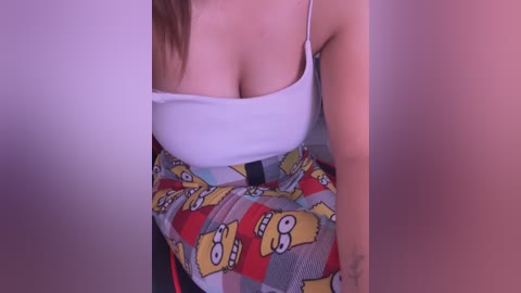 Video of a woman in a low-cut white tank top, revealing ample cleavage, and wearing a colorful skirt with The Simpsons characters, partially obscured by a pink background.