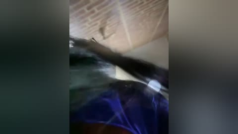 Media: Video of a man, possibly in his 30s, with dark hair and a medium build, wearing a dark blue suit and a white shirt, standing in a dimly lit room with textured beige walls.