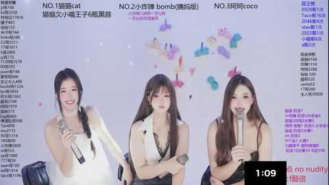 Video of three Asian women, one with long hair, another with braids, and the third with a ponytail, all singing into microphones against a colorful background, wearing casual outfits.
