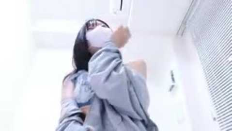 Video of an Asian woman with long black hair, wearing a gray shirt, raising her arm to the ceiling in a modern, brightly lit room with white walls and blinds.
