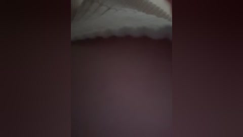 Video of a close-up of a human foot wearing a white sock, with a dark maroon background, emphasizing the sock's texture and the foot's contours.