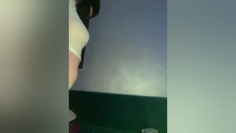 Video of a woman's lower body in a tight white dress, partially obscured by a dark, reflective surface. The background is a blurred, gradient blue and white.