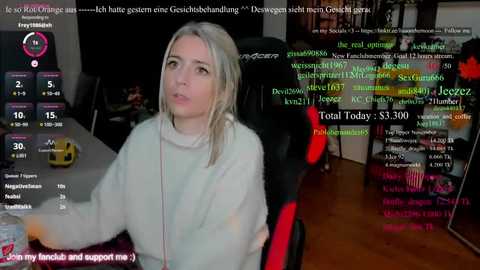 A video of a young woman with blonde hair in a gaming chair, wearing a white fuzzy sweater, surrounded by colorful chat text.