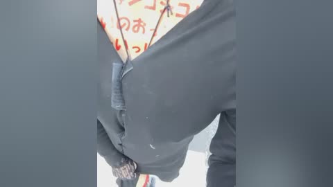 A close-up video of a person's hands, wearing gloves, pulling apart a plastic bag with Japanese text on it. The background is indistinct, and the image is in a blueish tone.