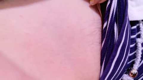 Video of a close-up of a person's chest, showing pale skin with faint red marks, and a partially unzipped blue and white striped shirt. The background is blurred.