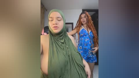 Video of two women: a light-skinned woman with long curly red hair in a blue patterned dress, and a darker-skinned woman in a green hijab, standing in a modern, brightly lit room with a gradient background.