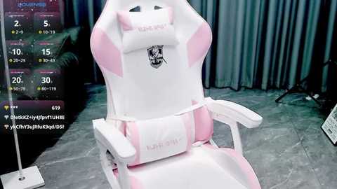 Video of a pink and white gaming chair with \"KONDO\" branding, set in a dimly lit room with gray curtains, a monitor displaying Twitch stream stats, and a laptop on the floor.