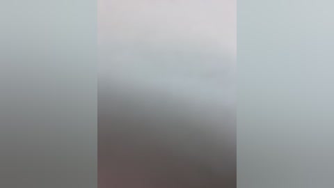 A video of a tall, vertical glass window with blurred, muted light entering from outside. The background is a soft gradient from pale blue to white, creating a serene, minimalist ambiance.