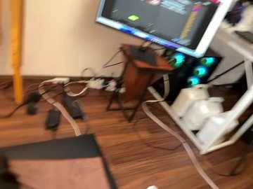 Media: A video of a cluttered office with a wooden desk, computer monitor displaying a colorful interface, scattered cables, and a white ceramic pot.