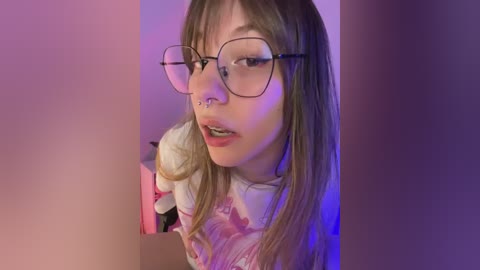Video of a young Asian woman with straight brown hair, wearing glasses, a nose ring, and a floral top, against a purple and pink background.