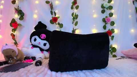 A video of a plush black panda toy, surrounded by fairy lights, faux roses, and a soft white blanket, creating a cozy, whimsical atmosphere.