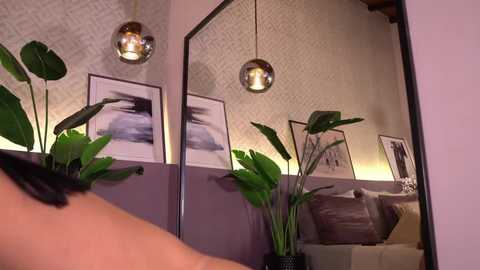 A video of a stylish, modern living room with a mirror, two potted plants, and framed art on lavender walls.