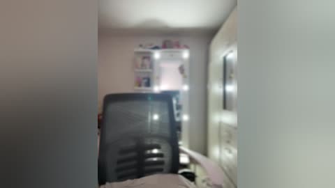 A video of a narrow, dimly lit bedroom with a cluttered closet, a bed with a white comforter, and a black chair partially visible in the foreground.
