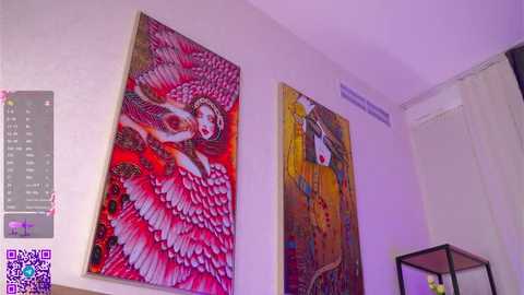 Video of a modern, colorful room with two large, abstract, feathered paintings in reds and purples, a QR code, and a black-framed table.