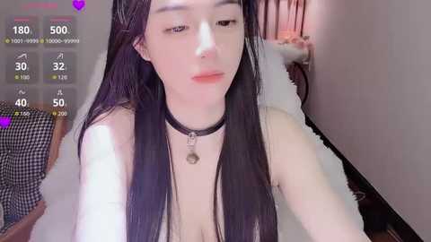 Video of a young Asian woman with long black hair, pale skin, and a black choker, in a bedroom with a purple heart overlay.