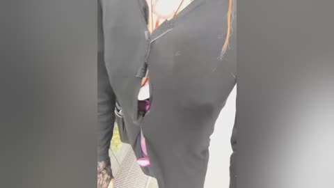 A video of a person wearing black leggings with a partially unzipped zipper, revealing a black sports bra underneath. The background is blurred, focusing on the subject's lower body.