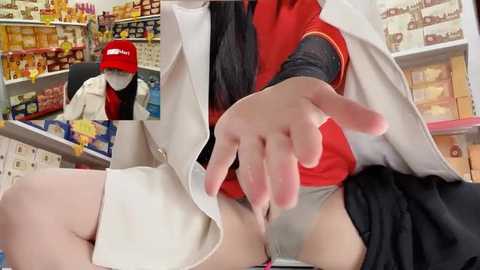 Video of a person in a white lab coat with a red shirt and black skirt, reaching out to a person in a red cap and white lab coat, in a supermarket aisle filled with snacks.