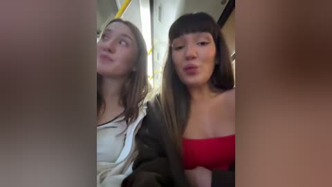 Media: Video of two young women in a subway car; one with long brown hair in a white top, the other with straight brown hair in a red strapless top.