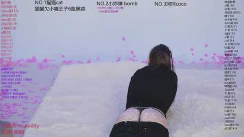 Video of a woman in a black top and pink lace panties, face down on a white bed with pink petals scattered around, surrounded by Chinese text.