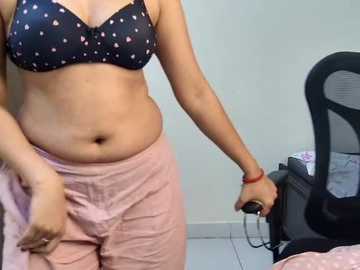 Video of a plus-sized woman in a black bra with white polka dots and pink shorts, holding a computer mouse in a modern office setting.