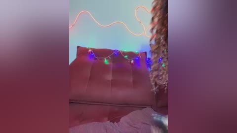 A blurry, festive photo shows a couch adorned with colorful string lights and a Christmas tree in the background, against a soft, muted wall.