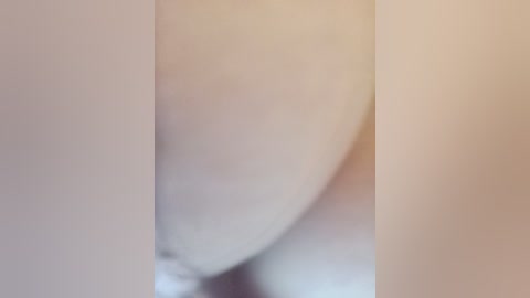 This is a close-up video of a smooth, light beige surface, possibly skin or fabric, with a soft, out-of-focus background. The image lacks distinct features or identifiable objects.