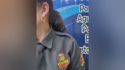 Video of a person wearing a dark green uniform with a yellow badge and a blue background featuring text and logos.