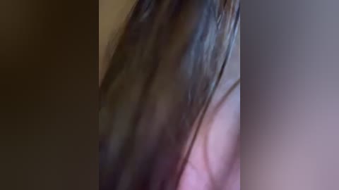 Media: A blurred close-up video showing dark, wet hair with strands falling downward, possibly from a person's head. The background is a muted, indistinct blur of various shades of brown and beige.