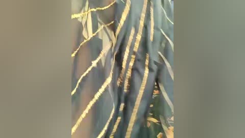 A video of a person wearing a long, flowing garment with intricate, gold-threaded designs on a dark blue background. The fabric appears silky and the person's body is slightly obscured by the flowing material.