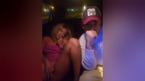 Video of a woman in a pink dress, leaning on a man in a baseball cap, both looking tired and contemplative in a dimly lit car.