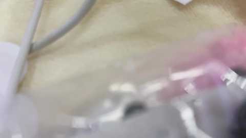 A close-up video of a surgical procedure, featuring a person's arm with a clear plastic drape covering it. The image is blurred, making details indistinct.