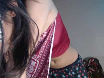 Media: Video of a light-skinned woman with long, dark hair partially covering her face. She wears a maroon crop top and black pants with a floral pattern, captured from a close-up, side angle.