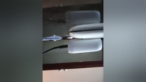 Video of a white desk chair with a curved backrest, positioned in a dimly lit room with a visible black cord and a white sheet draped over it, creating a minimalist, modern aesthetic.