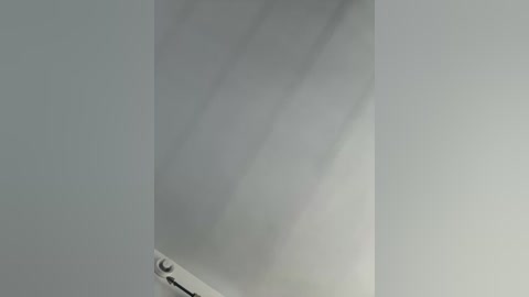 A video of a ceiling corner with a light fixture, casting soft shadows on the smooth, white ceiling. The image is taken from an angle, emphasizing the clean, minimalist aesthetic.